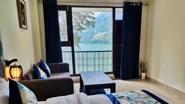 A hotel room with a balcony, a sofa, a bed, and a table. - The Lake Heritage @Bhimtal Lake (Nainital)