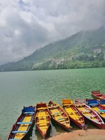 Un lago tranquilo con varias embarcaciones de madera amarradas a la orilla.