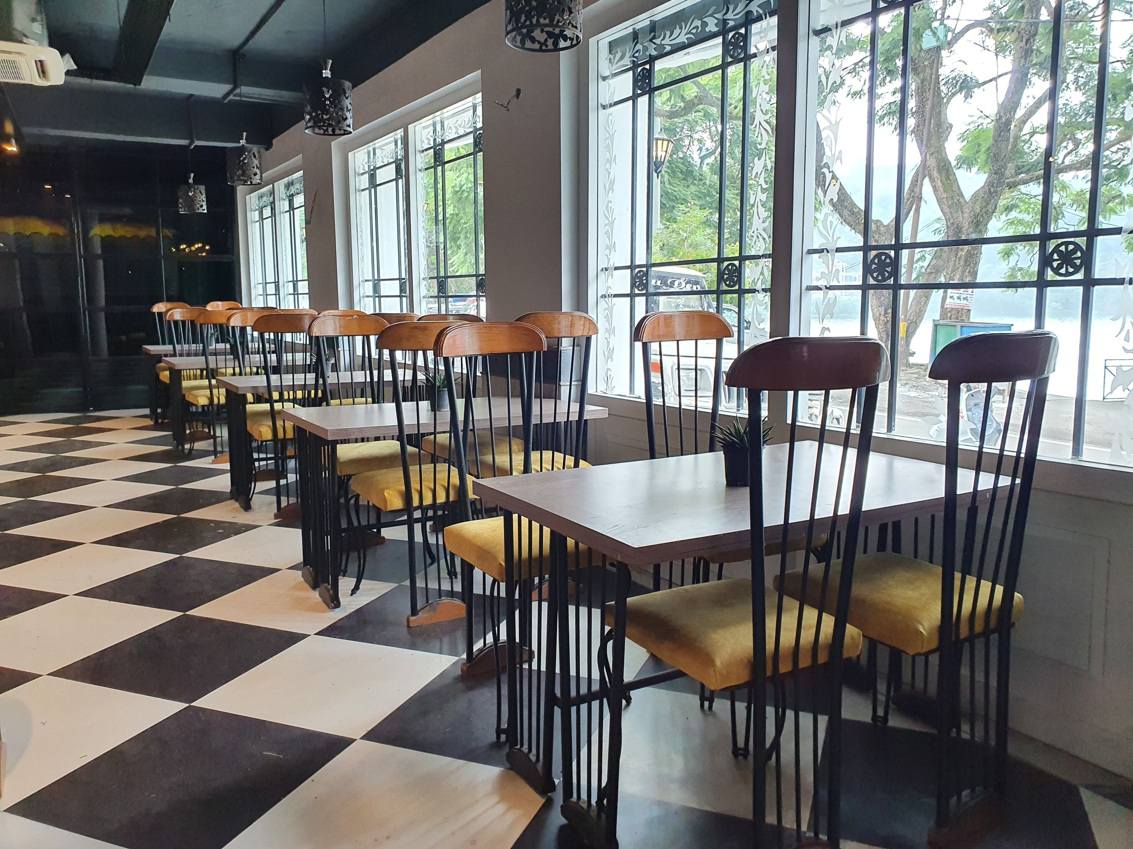 Un restaurante con suelo de cuadros, mesas de madera y sillas con cojines amarillos.