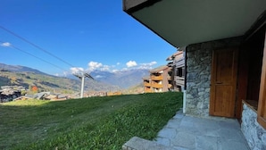 A building with a stone facade, a wooden door, and a grassy area in front.