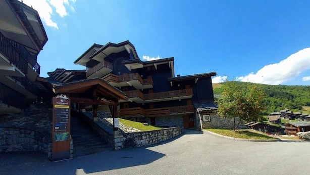 A traditional chalet-style building with a stone facade, wooden balconies, and a covered entrance.