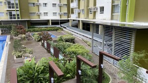 En flervåningsbostadsbyggnad med balkonger, en swimmingpool och ett vackert anlagt trädgårdsområde.