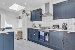 A modern kitchen with dark cabinets, a white countertop, and a skylight.