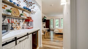 A kitchen with white cabinets, a brick wall, and shelves with kitchen items. - Perfect location. Home away from home. (Mont-Tremblant)
