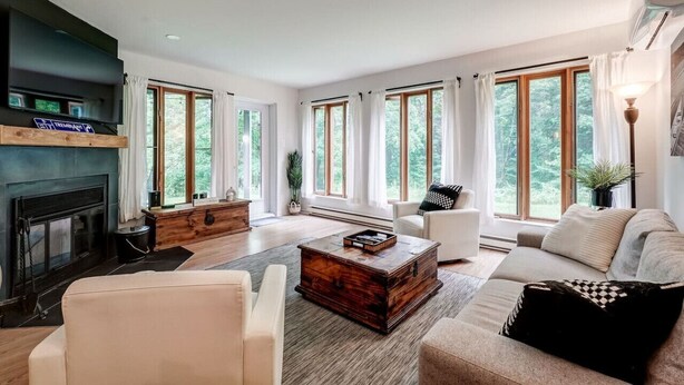 A spacious living room with a fireplace, large windows, and a cozy seating area. - Perfect location. Home away from home. (Mont-Tremblant)