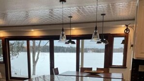 Ett rymligt kök med en stor köksö, vita skåp och hängande lampor.