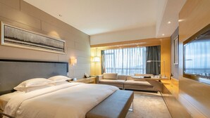 A hotel room with a large bed, a sofa, a desk, and a window with curtains. - Huangyan Yaoda Hotel (Taizhou)