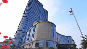 A modern hotel with a curved facade, a prominent entrance, and a flagpole. - Huangyan Yaoda Hotel (Taizhou)