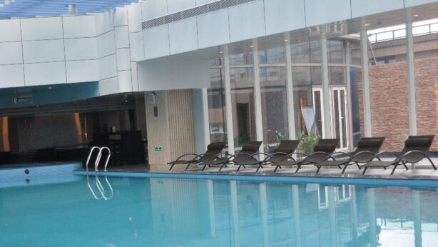 A swimming pool with lounge chairs and a glass-enclosed area. - Huangyan Yaoda Hotel (Taizhou)