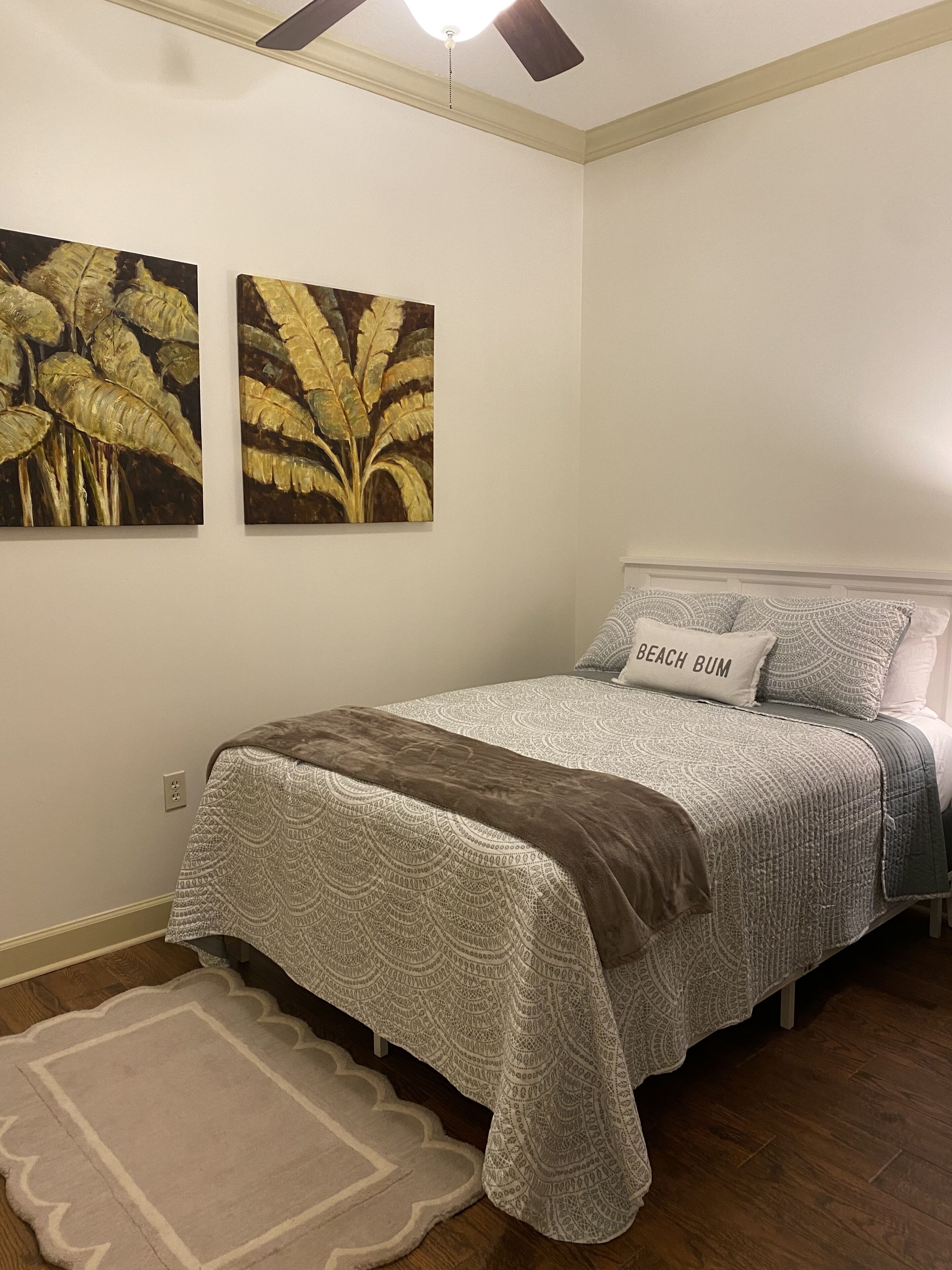 Une chambre à coucher avec un lit, un tapis et deux tableaux accrochés au mur.