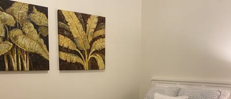 Une chambre à coucher avec un lit, un tapis et deux tableaux accrochés au mur.