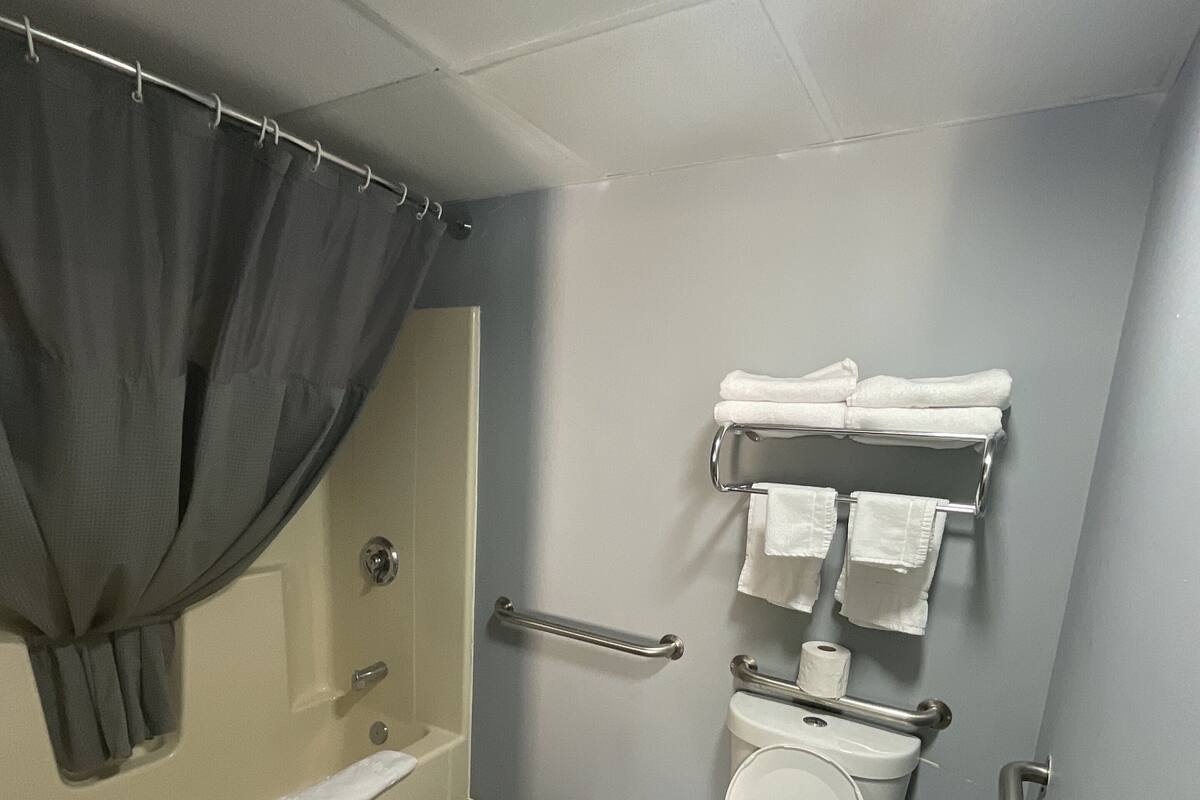 Kylpyhuone, jossa on suihku, wc ja tukikaiteet.