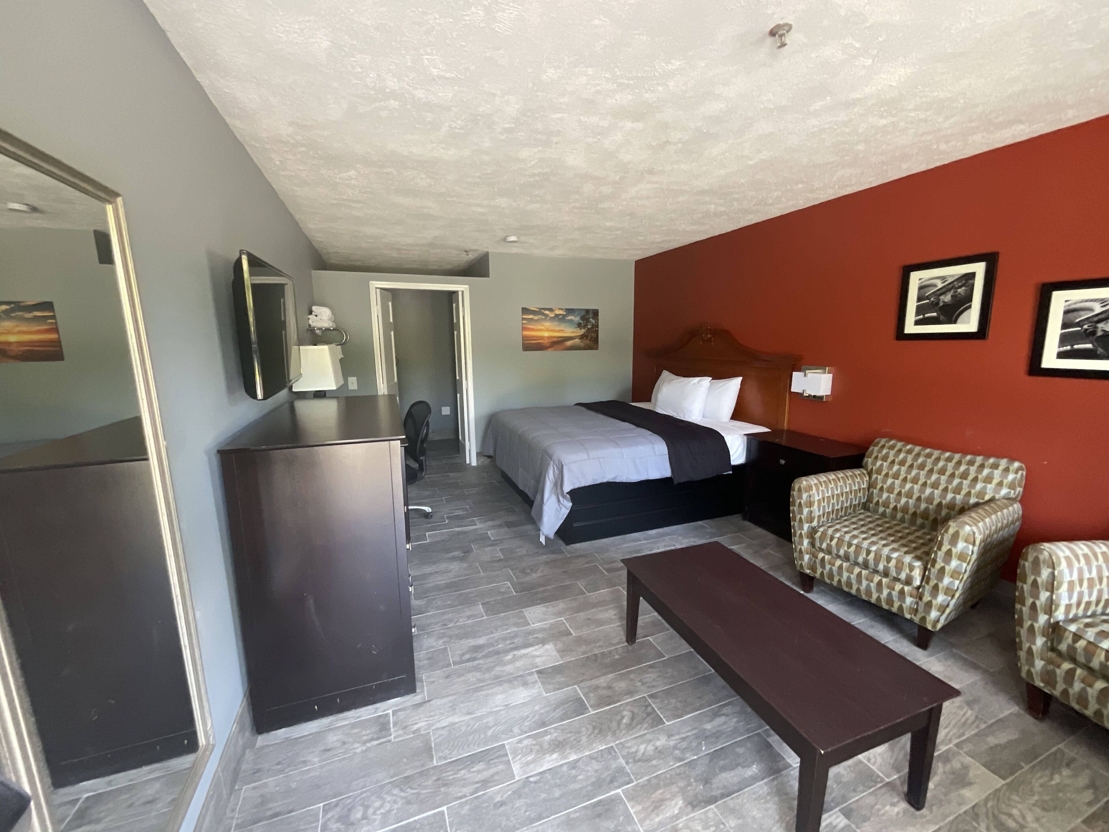 A hotel room with a bed, a desk, a chair, and a small table.