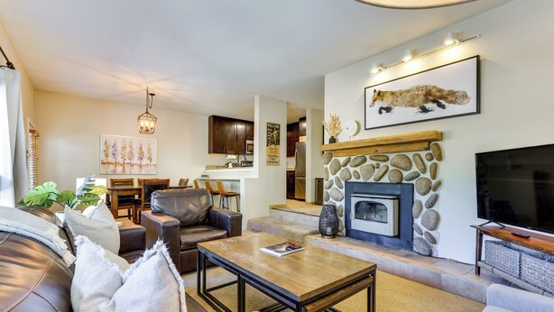 A modern living room with a stone fireplace, leather sofa, and a television. - East Vail Condo w/ Pool, Hot Tub, & Free Bus Stop (Vail)