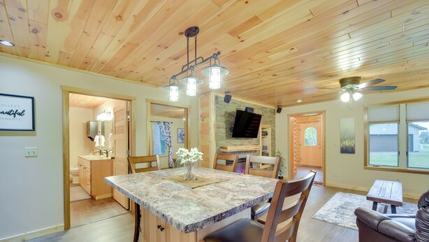 A spacious living area with a wooden ceiling, a central island with seating, and a television mounted on the wall. - Cozy Cable Cabin Rental - Pet Friendly! (Cable)