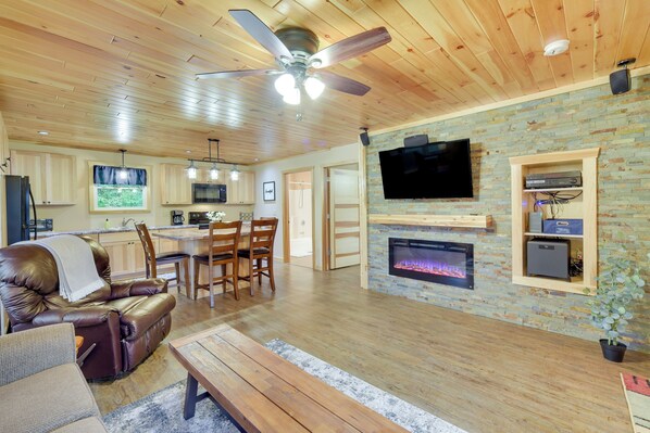 A living room with a fireplace, a television mounted on the wall, and a ceiling fan.