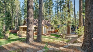 A cabin surrounded by tall pine trees, with a stone pathway leading to the entrance. - Hike, Boat & Ski: South Lake Tahoe Home (South Lake Tahoe)
