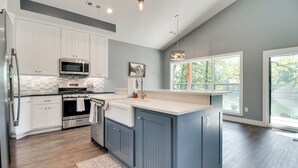 A modern kitchen with white cabinets, a built-in microwave, and a large island with blue cabinets. - Riverfront Salesville Cabin Rental w/ Shared Dock! (Mountain Home)