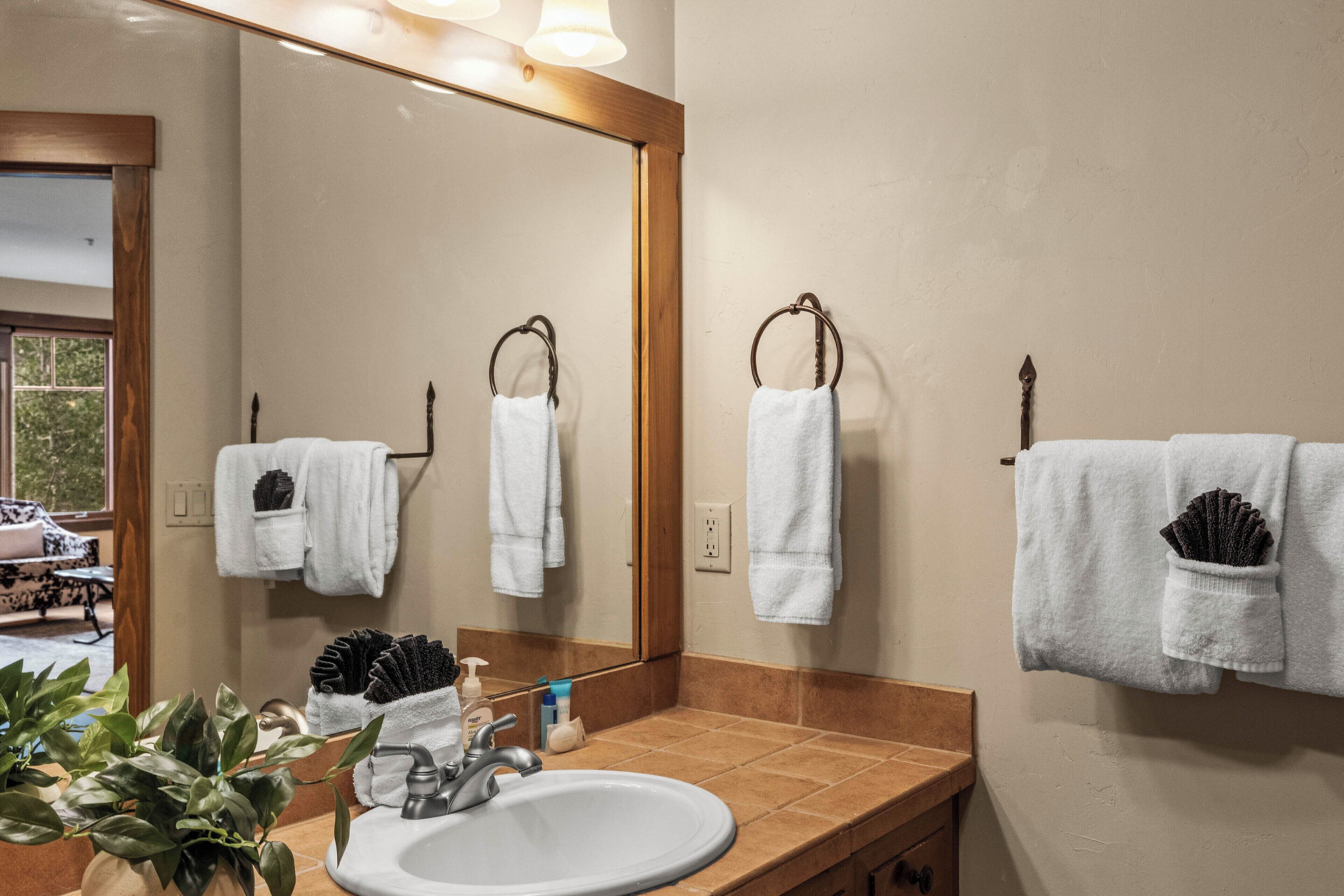 Un baño con un espejo grande, un lavabo y dos barras para toallas.