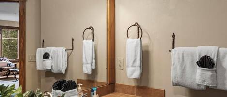 Un baño con un espejo grande, un lavabo y dos barras para toallas.