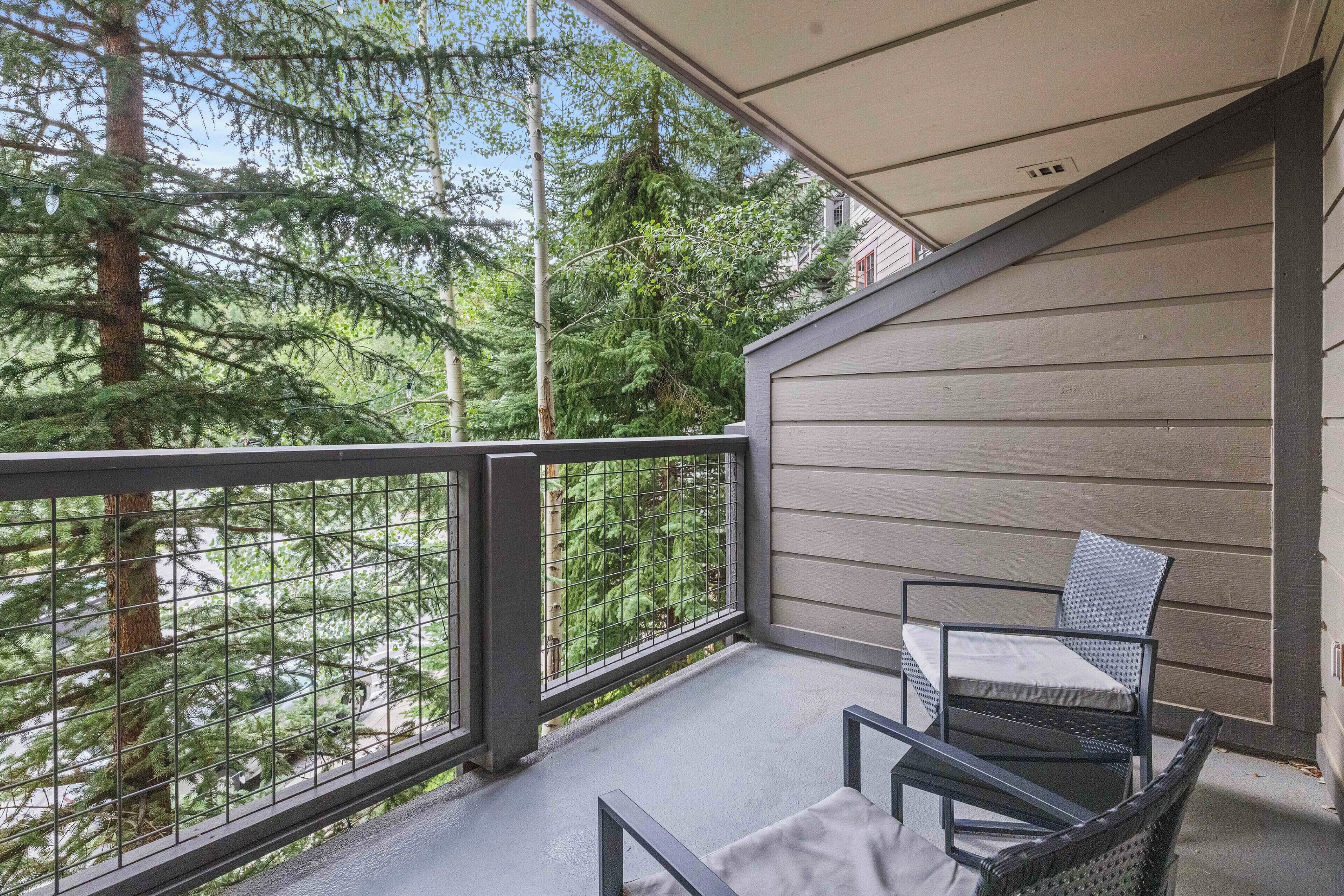 A balcony with a metal railing, a chair, and a table.