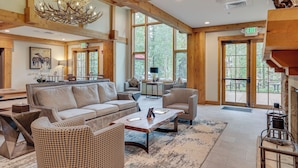 A spacious living area with a large sofa, patterned chairs, a coffee table, and a chandelier.