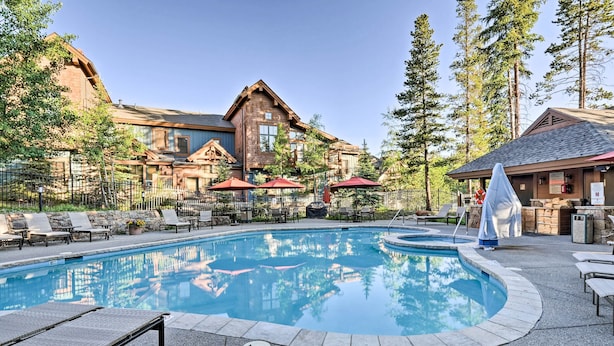 A pool area with lounge chairs, umbrellas, and a building with a stone facade.