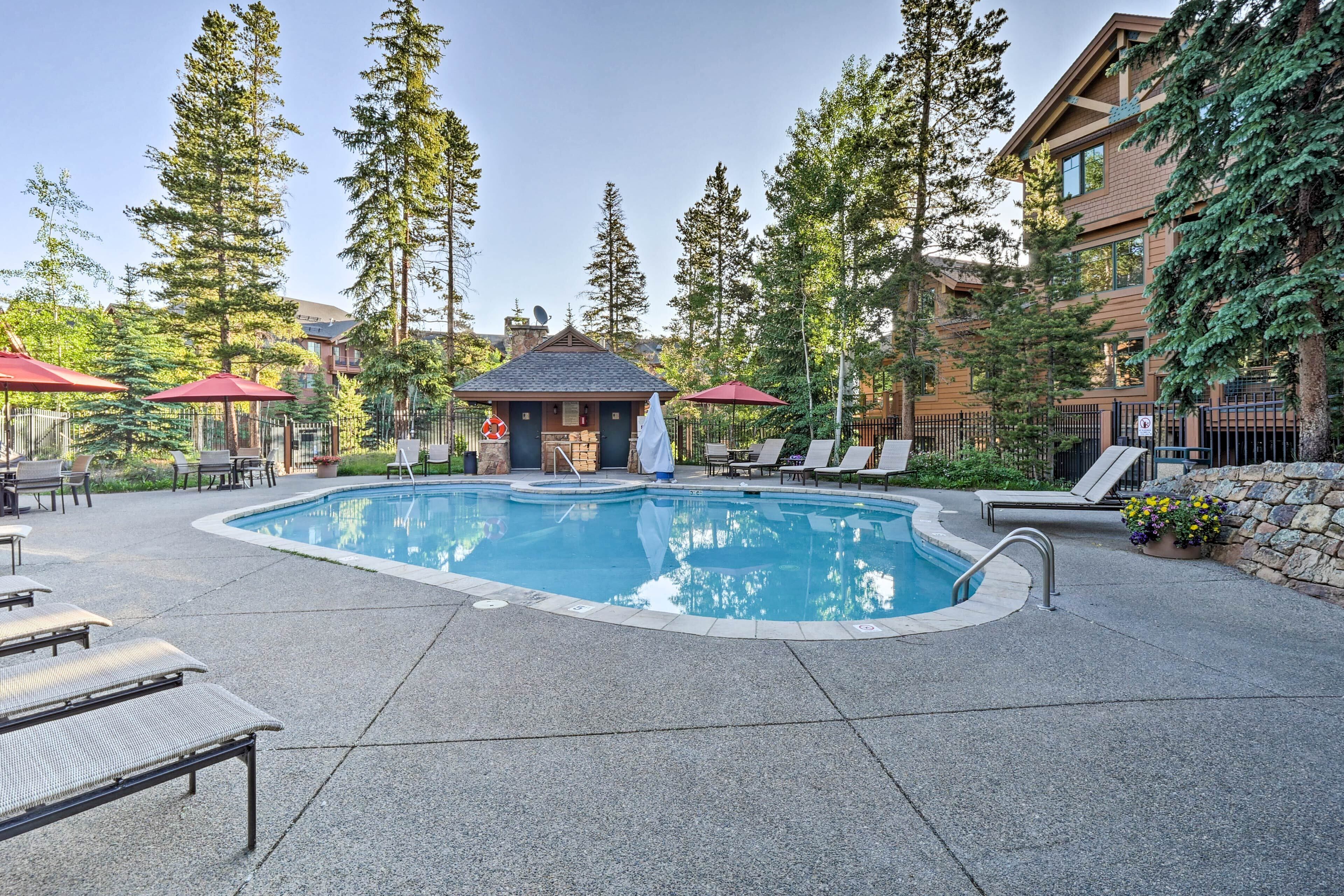 A pool area with lounge chairs, a small gazebo, and tall trees.