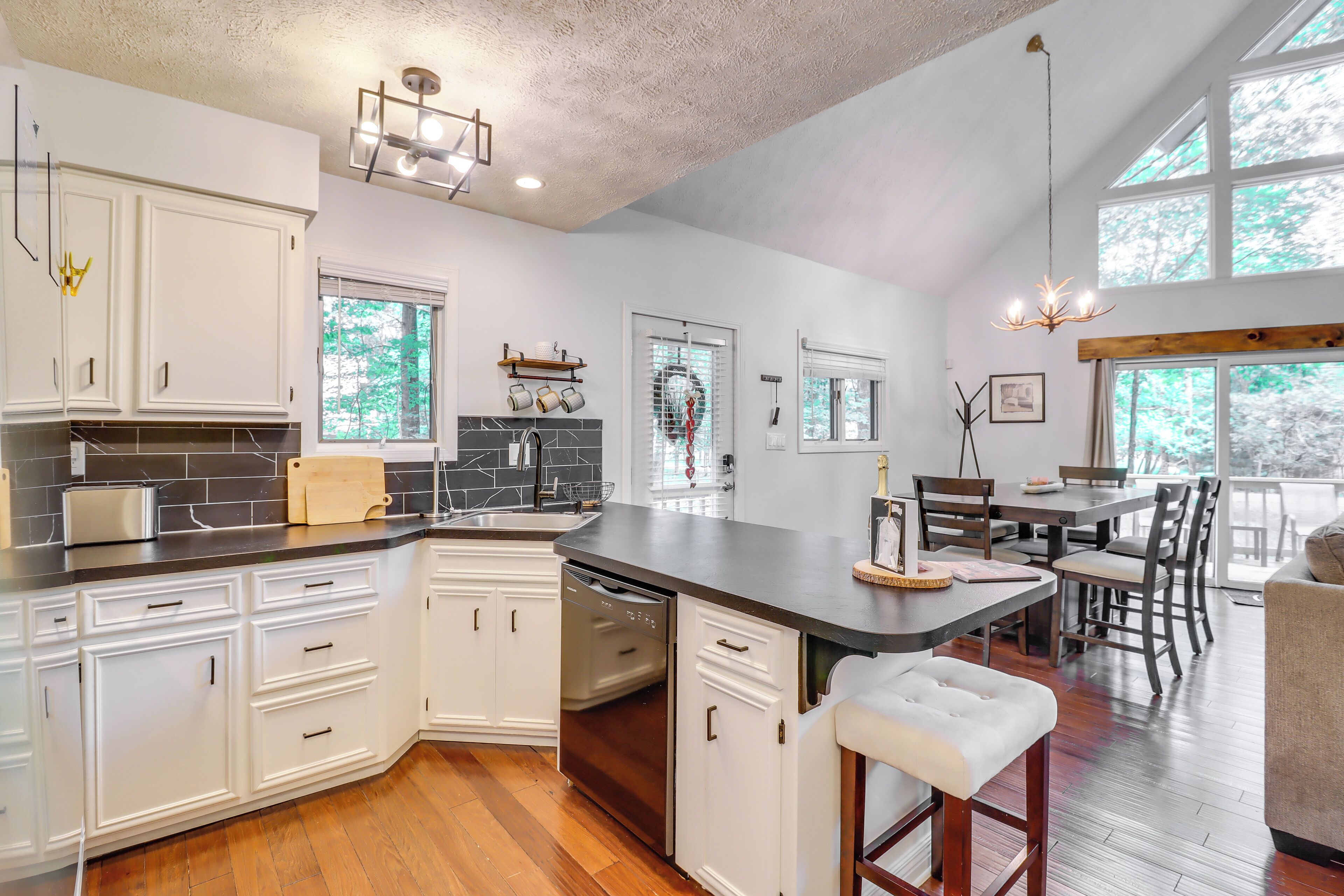 A modern kitchen with white cabinetry, a built-in dishwasher, and a large island with stools.