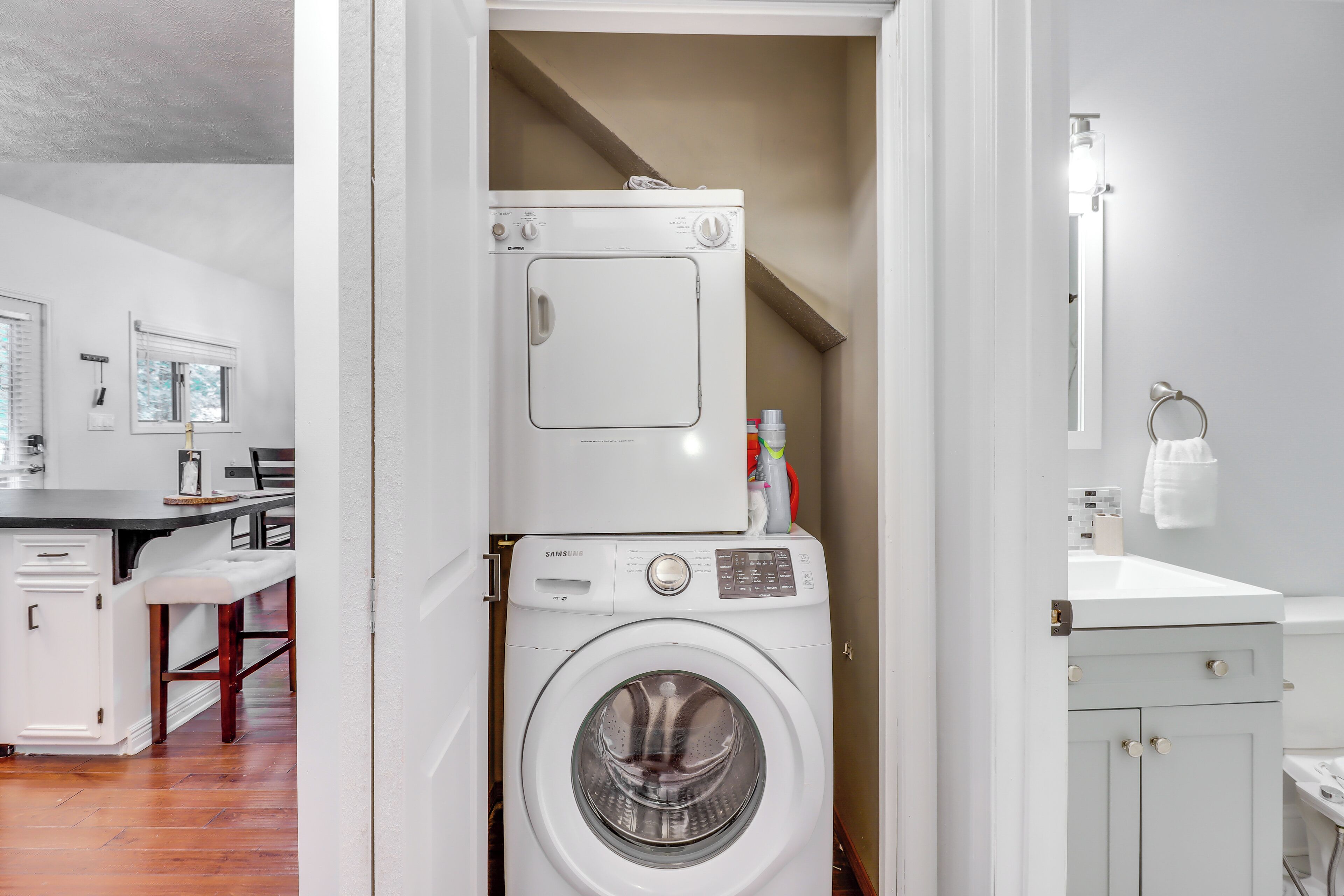 A laundry room with a front-loading washing machine, a dryer, and a small cabinet.