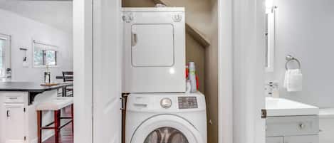 A laundry room with a front-loading washing machine, a dryer, and a small cabinet.