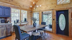 L’intérieur d’un chalet en bois comprend une table à manger, des chaises, un coin bar et une grande fenêtre.