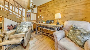 A cozy room with a wooden staircase, a plush armchair, a sofa, and a small table with a lamp. - Ruidoso Cabin w/ Deck + Views: 4 Mi to Winter Park (Ruidoso)