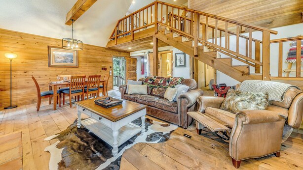 A spacious living room with a wooden staircase, a dining area, and a cozy seating arrangement. - Ruidoso Cabin w/ Deck + Views: 4 Mi to Winter Park (Ruidoso)