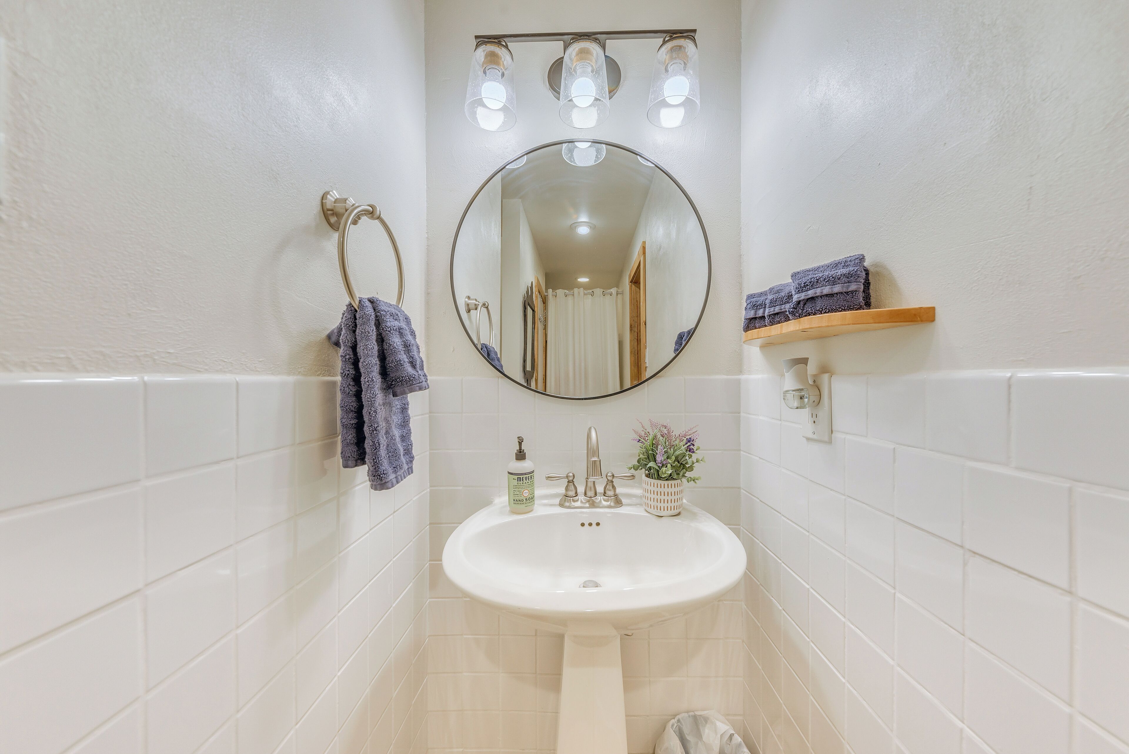 A bathroom with a white sink, a round mirror, and a towel rack.