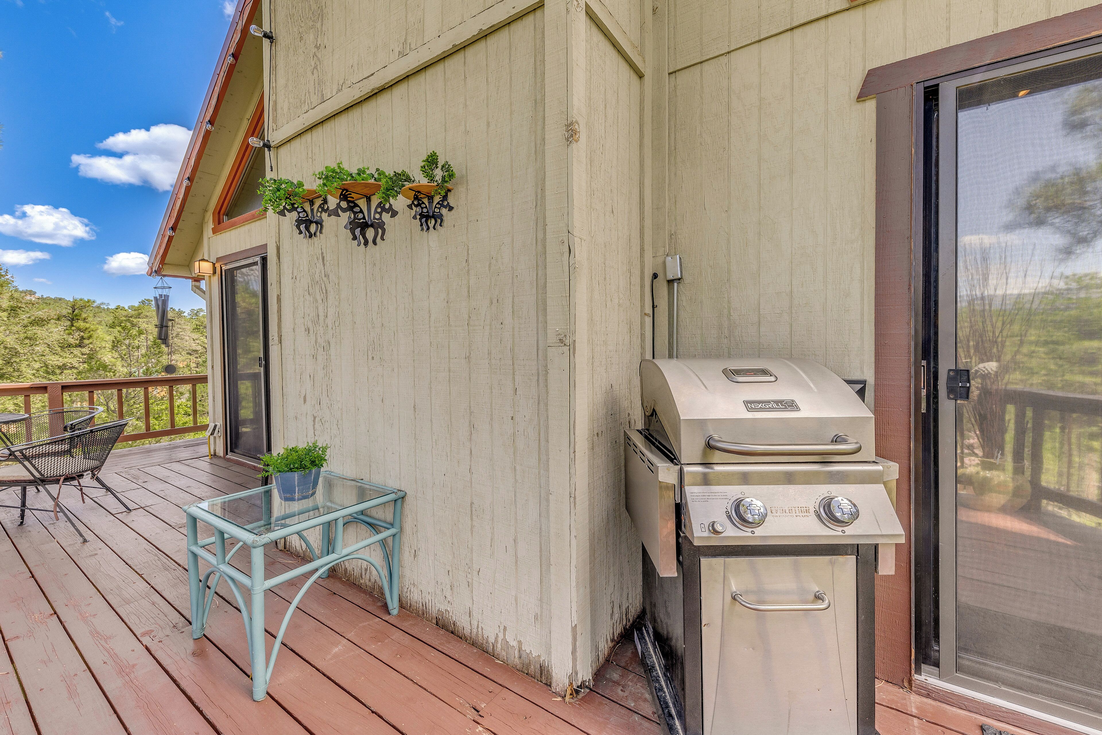 A deck with a grill, outdoor furniture, and hanging plants.