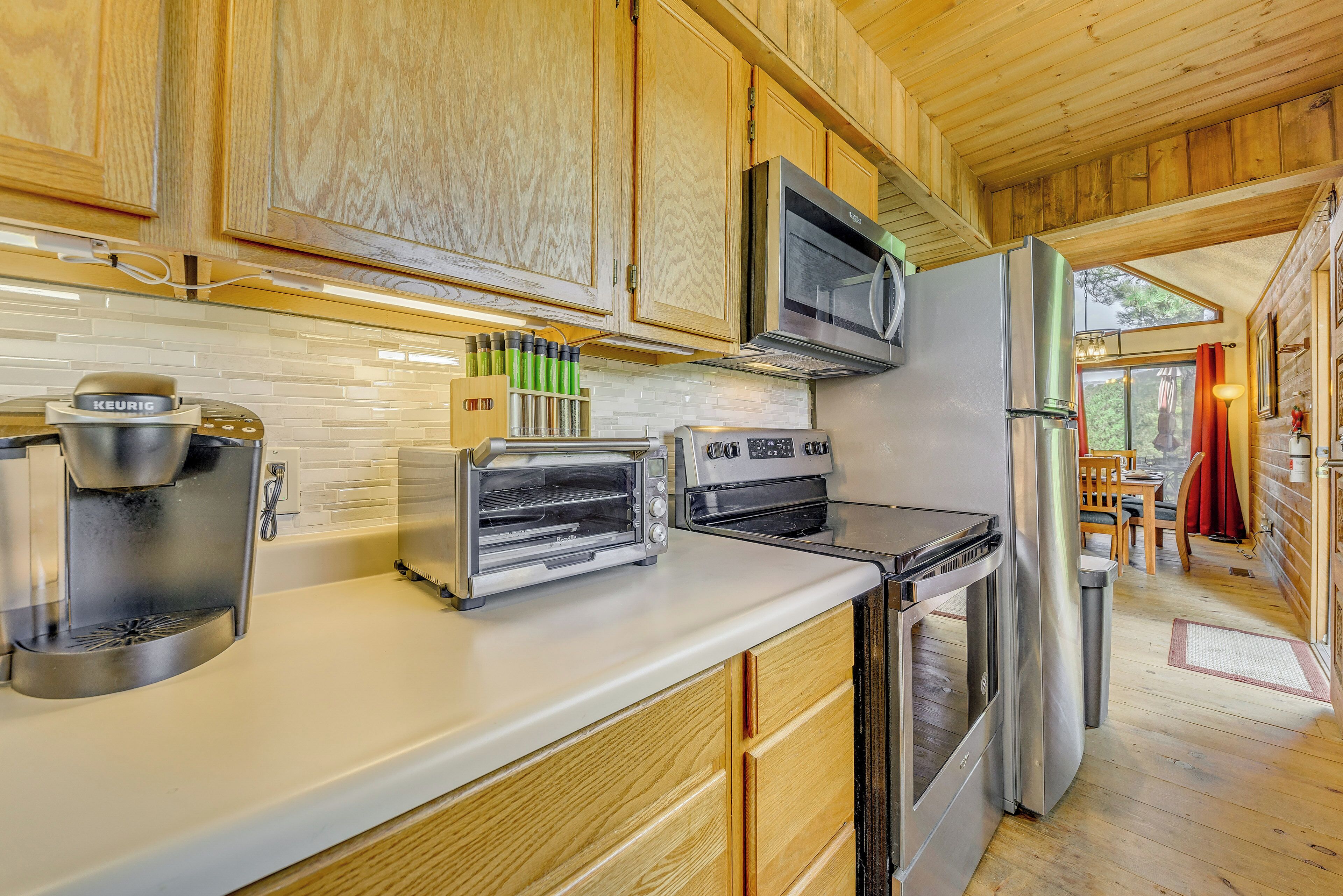 A modern kitchen with wooden cabinets, a stainless steel refrigerator, a microwave, a coffee maker, and a toaster oven.