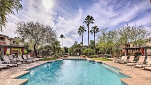 A rectangular swimming pool with clear blue water, surrounded by lounge chairs and palm trees. - Walk to Papago Park: Central Phoenix Condo (Phoenix)