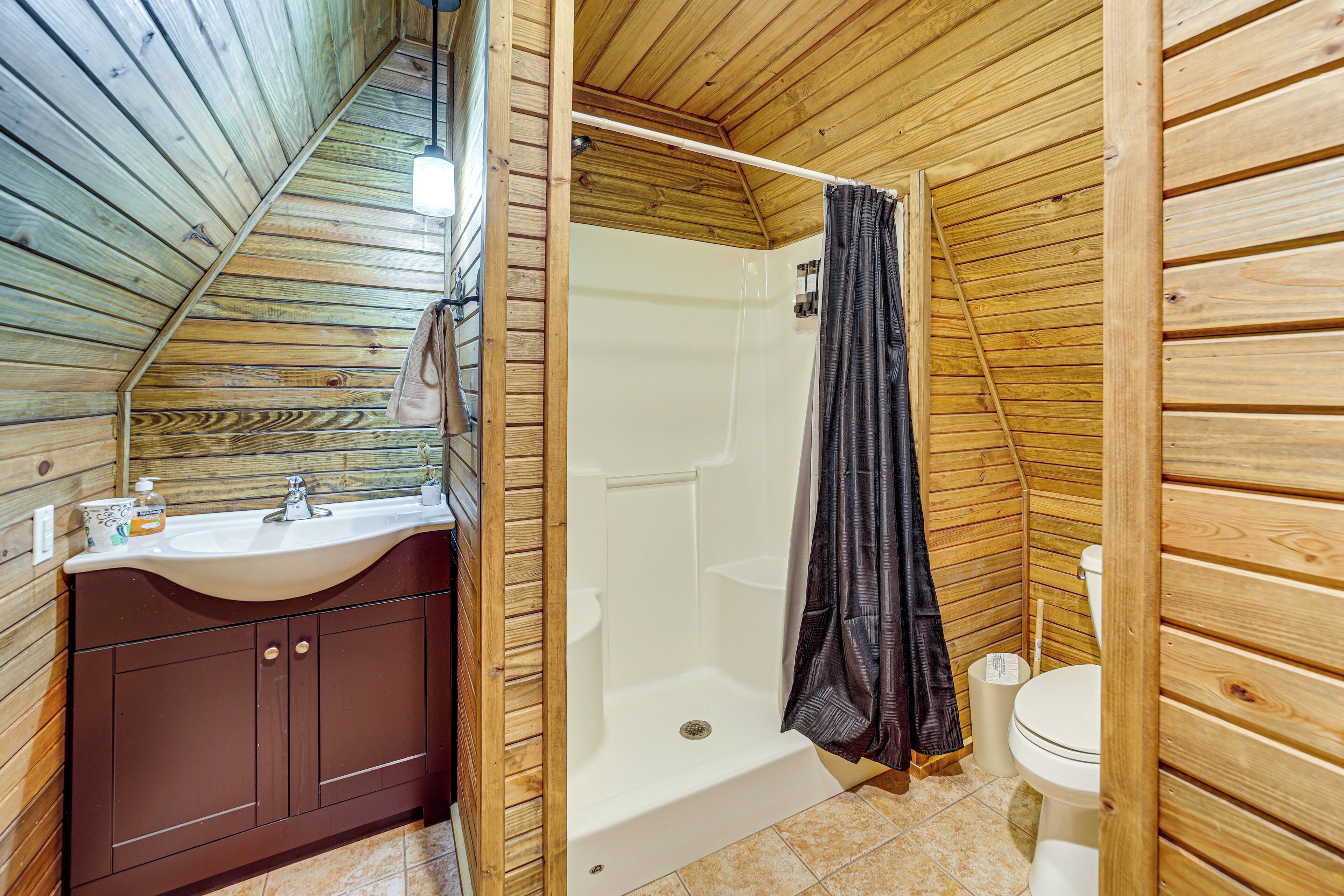 Bagno di una casetta in legno, con lavandino, water e doccia.