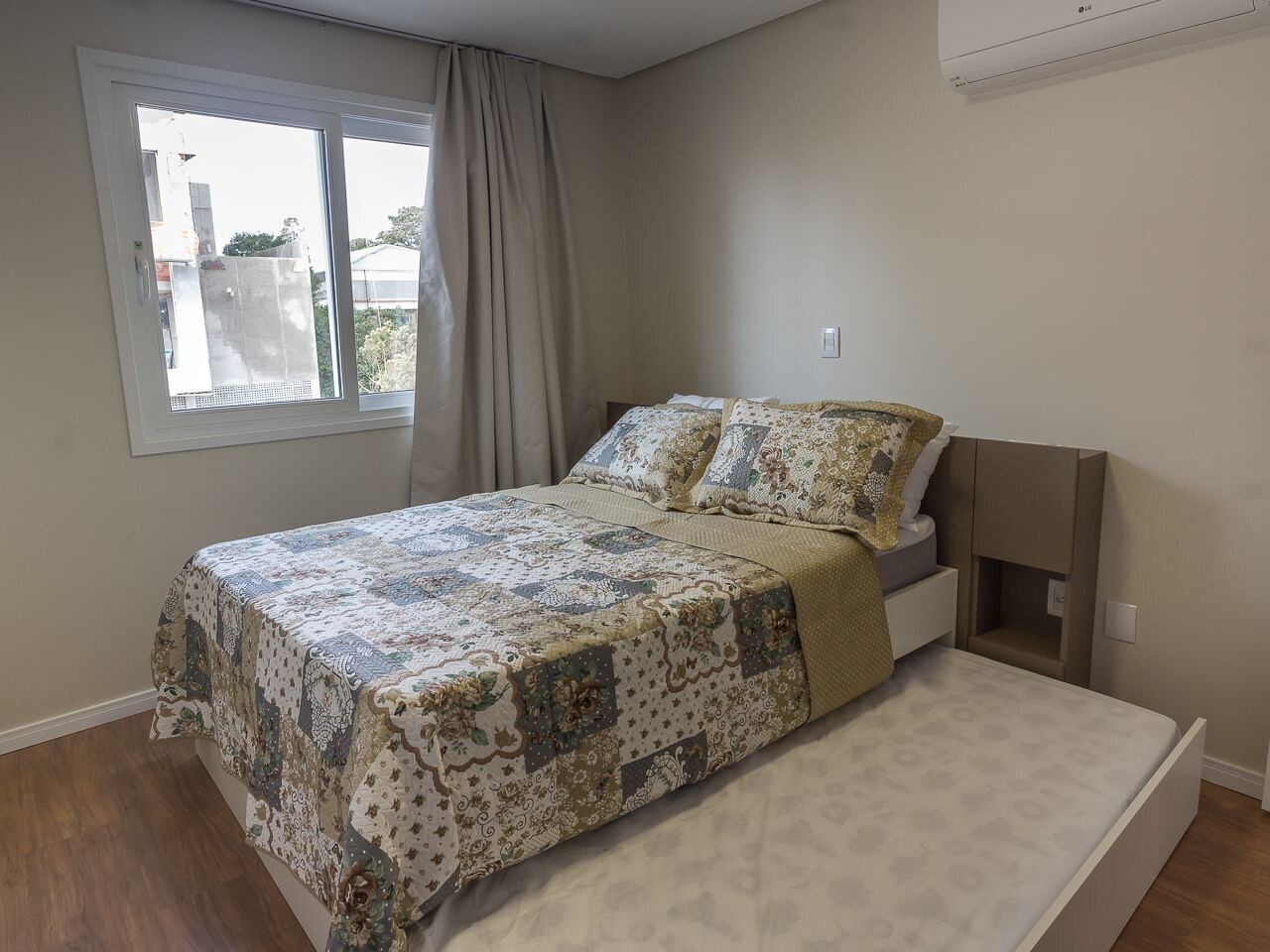 Un dormitorio con cama, ventana y mesita de noche empotrada.