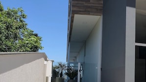 A modern building with a tiled patio area, a clear sky, and some greenery. - Dallas Apartamentos (Bento Gonçalves)