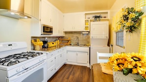 Una cocina compacta con alacenas blancas, estufa a gas, microondas y refrigerador.