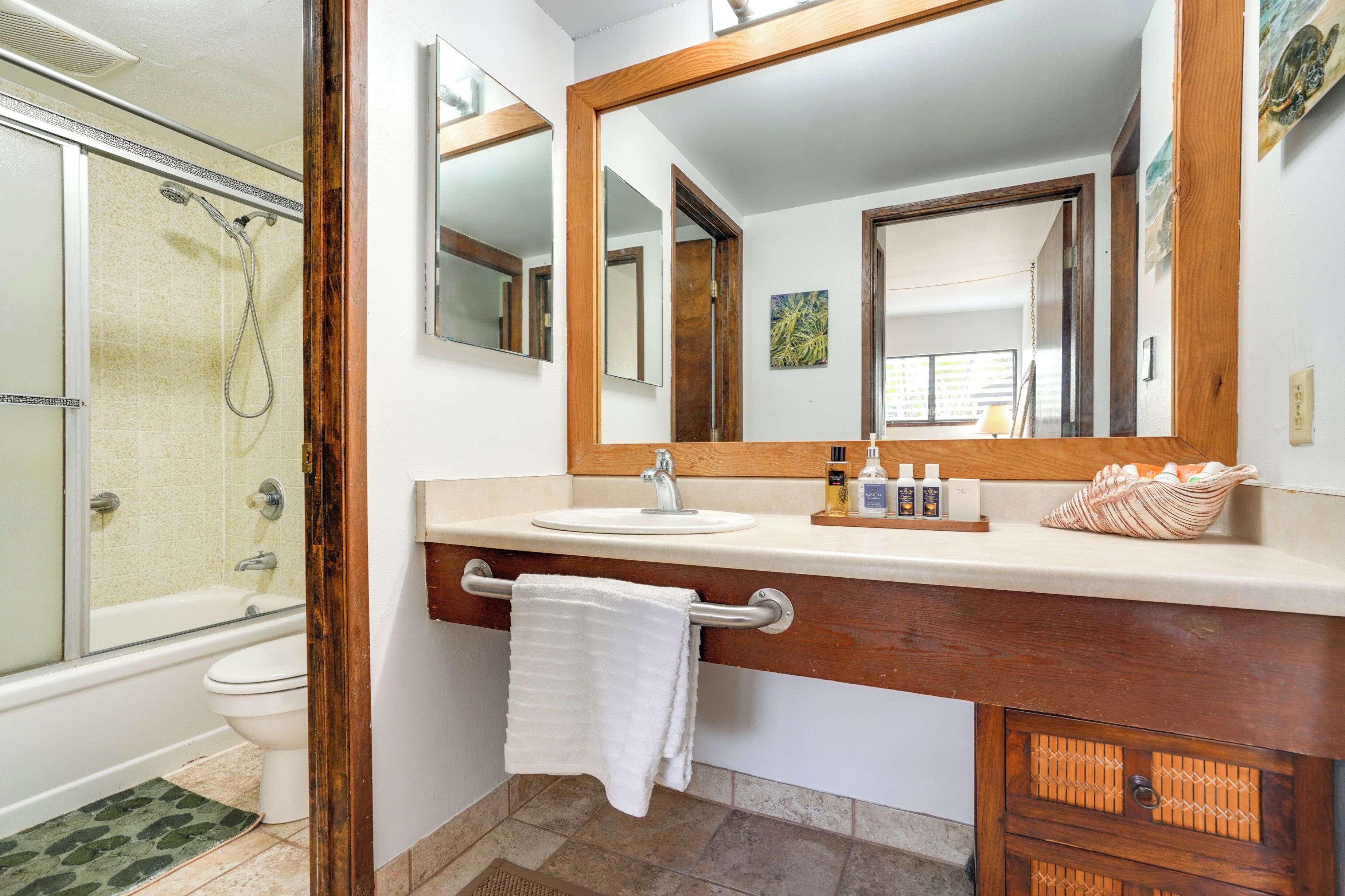 A bathroom with a shower, toilet, sink, and a large mirror.