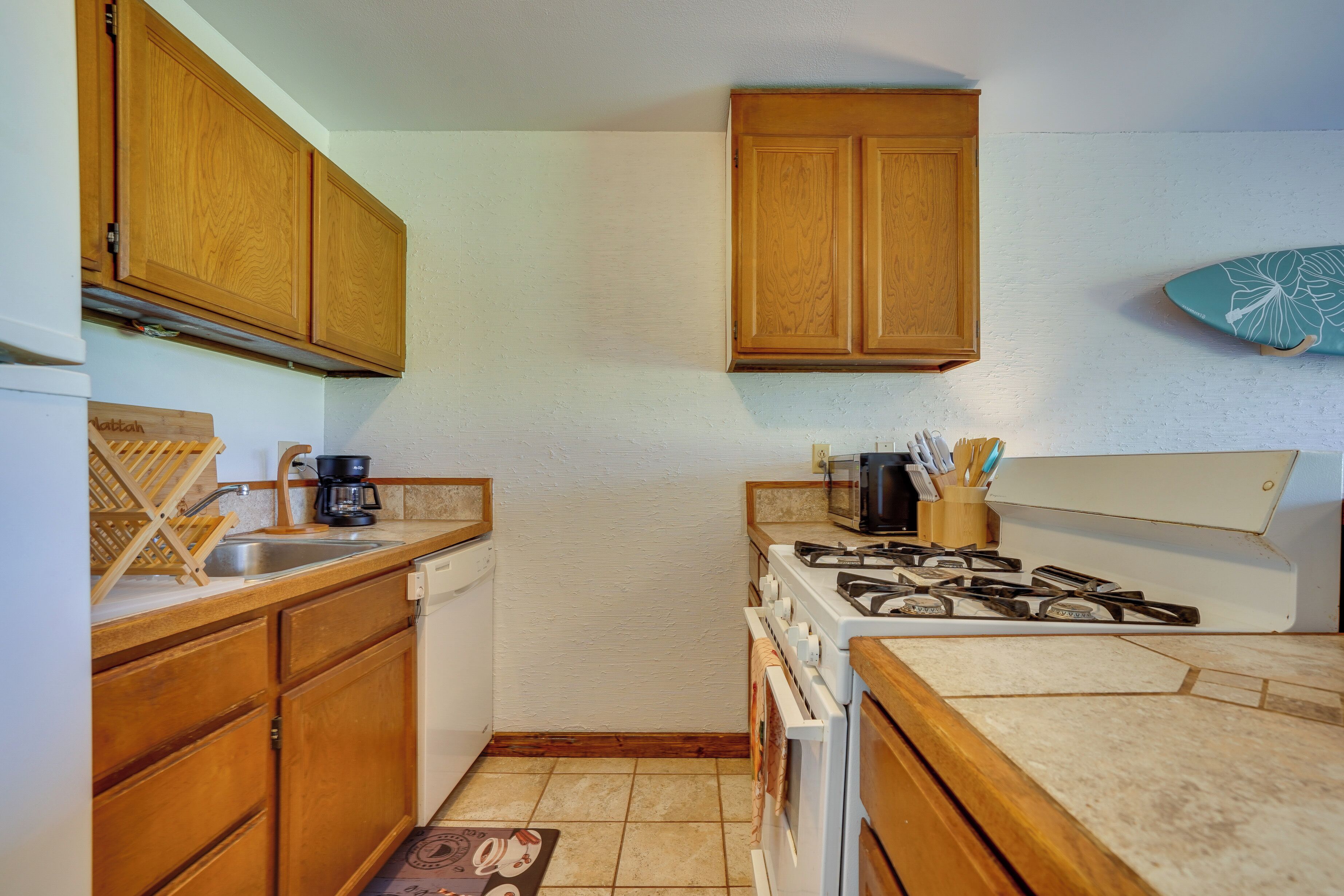 A compact kitchen with wooden cabinets, a gas stove, a microwave, and a sink.