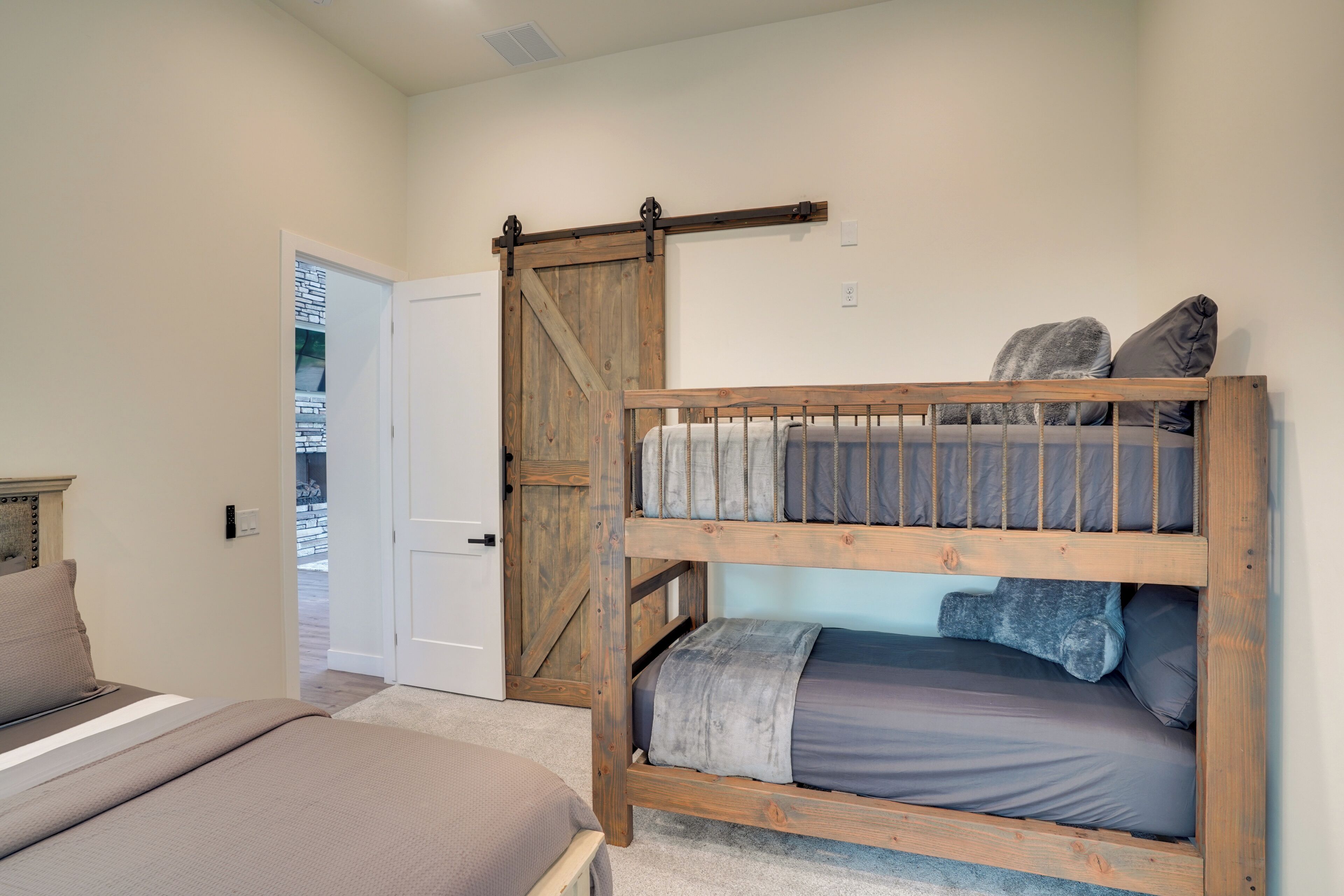 A bedroom with a bunk bed, a door, and a bed with a headboard.