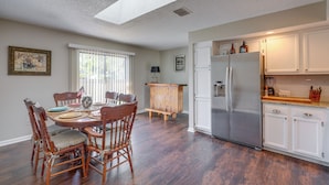A dining area with a wooden table and chairs, a kitchen with white cabinets and a stainless steel refrigerator, and a skylight above. - Ponte Vedra Beach Family Home: 2 Mi to Beaches! (Ponte Vedra Beach)