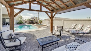 Un espacio al aire libre con techo, piscina, sillas de descanso y una mesa de patio.