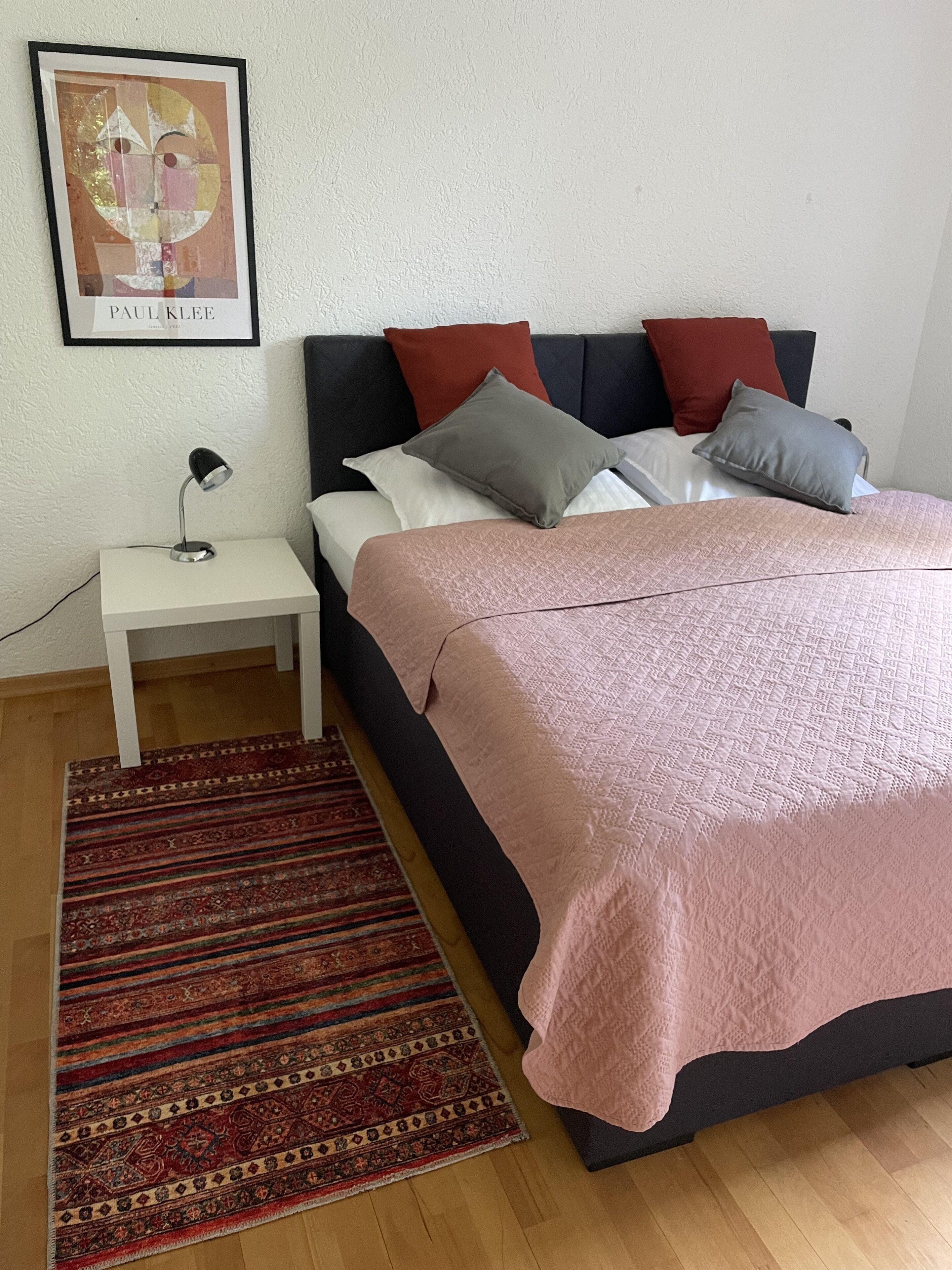 A bedroom with a bed, nightstand, and a framed picture on the wall.