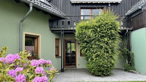 A house with a green exterior, a black roof, and a large bush in front. - Behagliches Haus mit Kamin (Monschau)