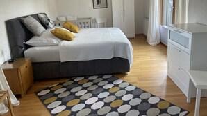 A bedroom with a bed, bedside table, wardrobe, and a window with curtains. - Behagliches Haus mit Kamin (Monschau)